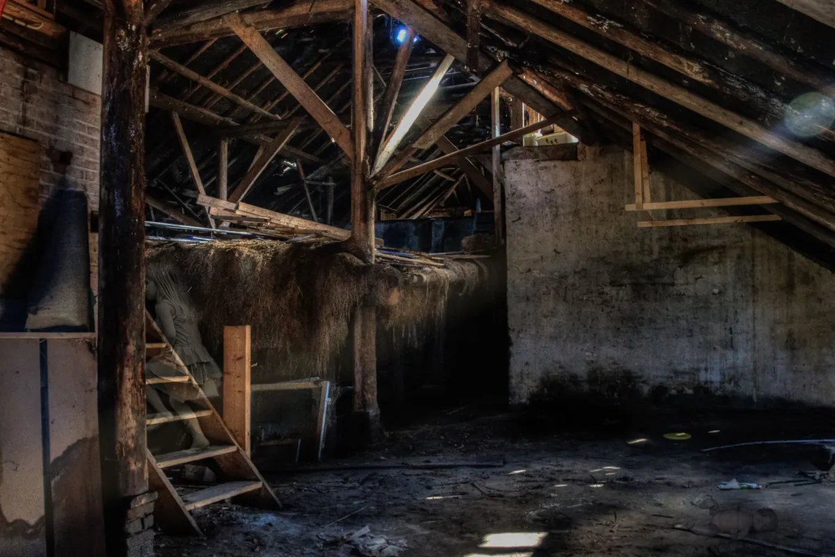 Dusty attic with wooden beams and shafts of sunlight