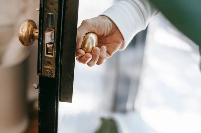 Hand turning a brass door knob on an open door