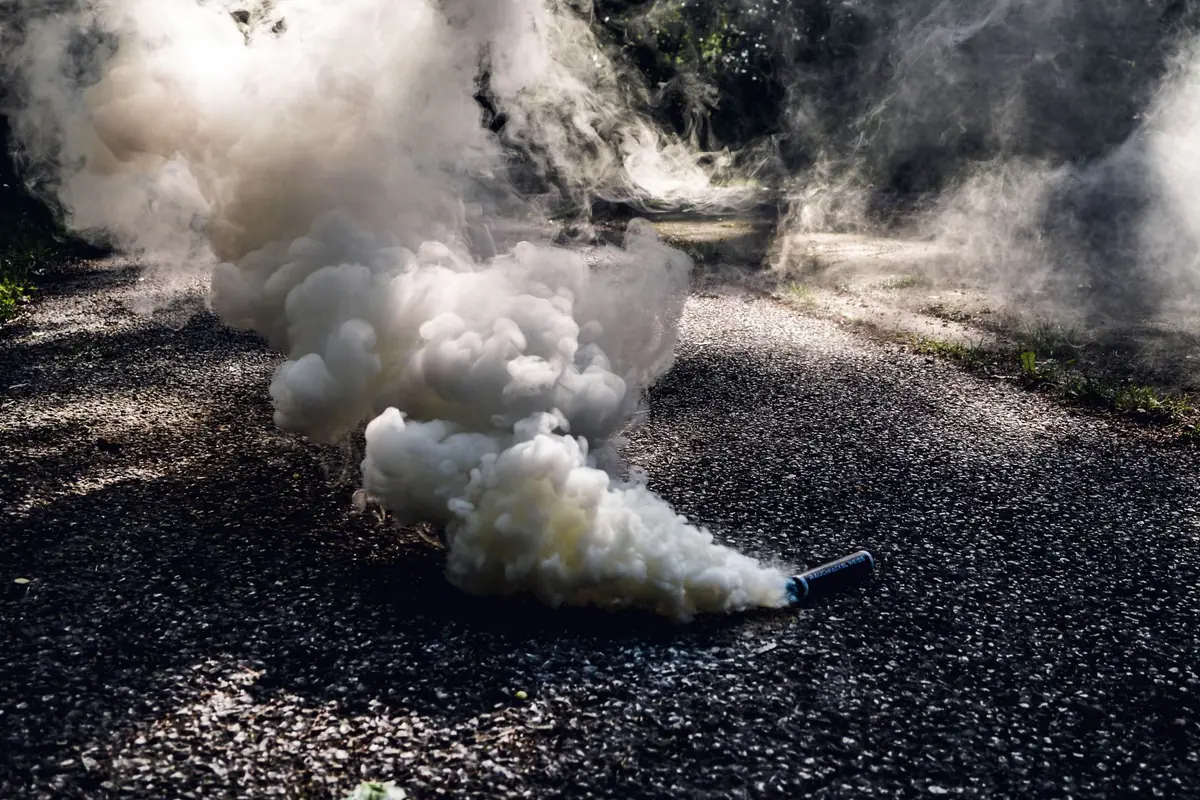 White smoke drifting across a shaded gravel path